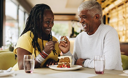 Couple smiling while enjoying slice of cake together