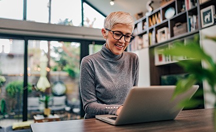 Woman smiling while working on laptop at home