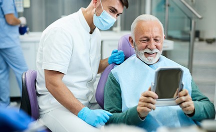 Man smiling while looking at reflection in handheld mirror