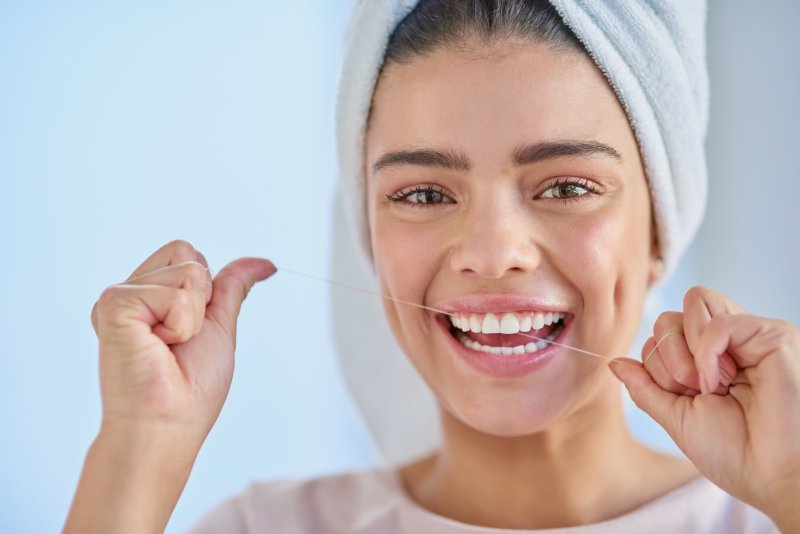 A happy, smiling woman flossing between her teeth